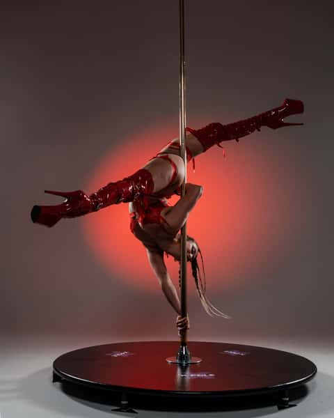 Pole performer in cold-key studio mid-pose