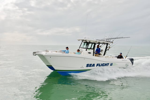 Anglers aboard the Sea Flight II charter boat cruising green Gulf waters under a cloudy sky