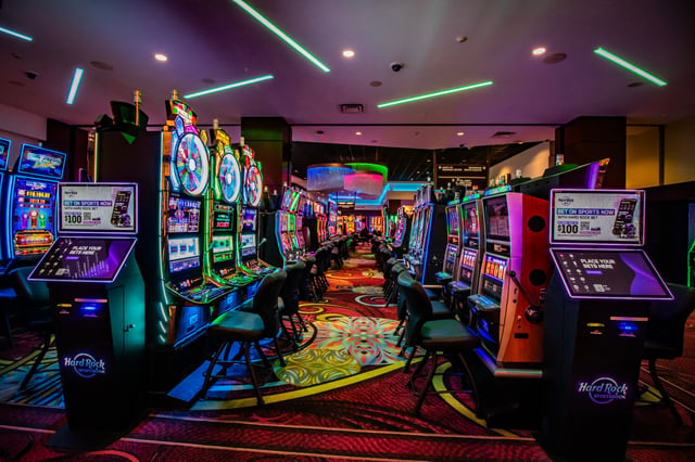 Rows of glowing slot machines and Hard Rock sportsbook kiosks line a neon-lit gaming floor at Seminole Casino Hotel Immokalee