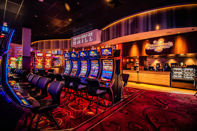 Rows of glowing slot machines and swivel chairs on patterned red carpet inside Seminole Casino Hotel Immokalee