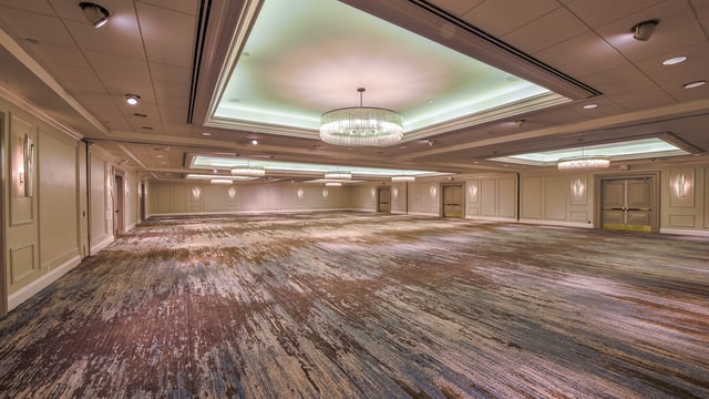 Empty Orchid Ballroom with patterned carpet, crystal chandeliers and a softly lit coffered ceiling