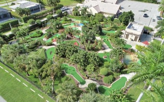 Aerial view of Marco Golf and Garden showing winding green mini golf holes surrounded by tropical palms and gardens