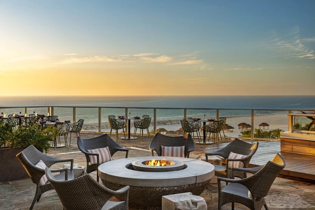 Rooftop terrace at Tesoro with a round fire pit, wicker chairs and Gulf views at sunset