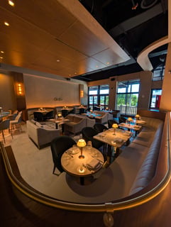 Modern dining room at Ce Soir with curved leather banquettes, set tables and warm lamp lighting