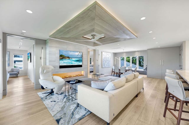 Bright coastal living room with white sectional, linear fireplace, wall-mounted TV and wood-paneled ceiling detail