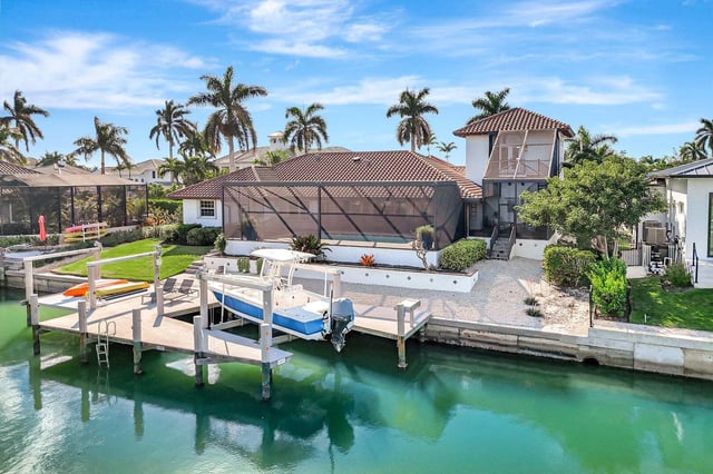 Waterfront home with screened lanai, private dock and boat lift on a calm green canal lined with palms