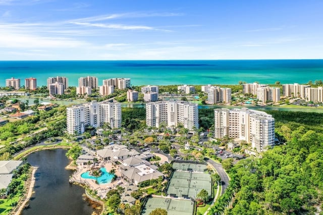 Aerial view of high-rise condo towers, resort pool, tennis courts and lakes along the turquoise Gulf coast