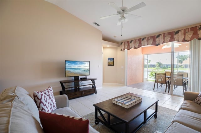 Bright living room with vaulted ceiling, ceiling fan, flat-screen TV and sliding doors to a screened lanai
</result>