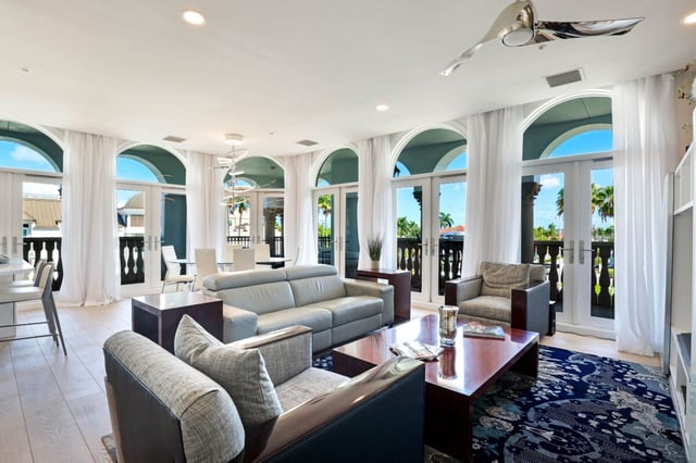 Bright coastal living room with arched French doors, white curtains, gray sofas and a blue patterned rug