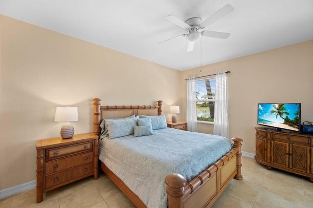 Bedroom with a wooden four-poster bed, light blue bedding, ceiling fan, flat-screen TV and tile floor