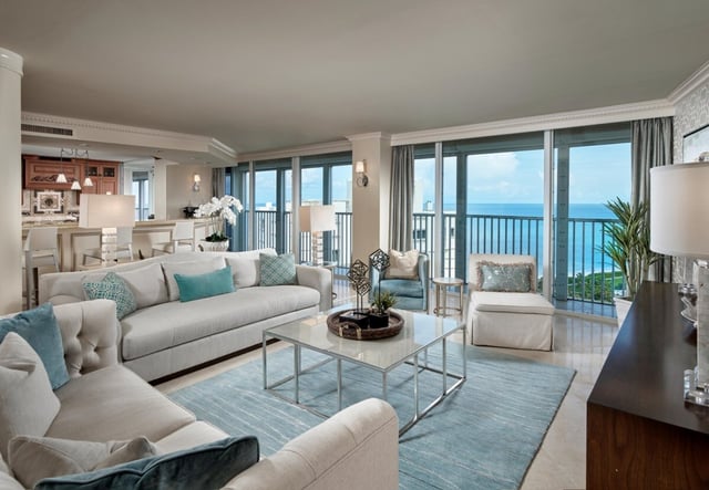 Spacious condo living room with white sofas, turquoise accents and floor-to-ceiling windows overlooking the Gulf