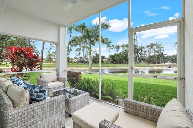 Screened lanai with white wicker furniture and blue pillows overlooking a lake, palms and green lawn
Screened lanai with white wicker furniture and bl