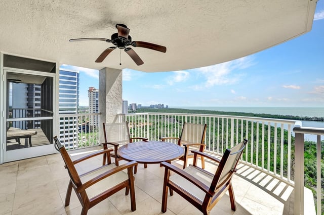 High-rise condo balcony with ceiling fan, round patio table and chairs overlooking mangroves and the Gulf