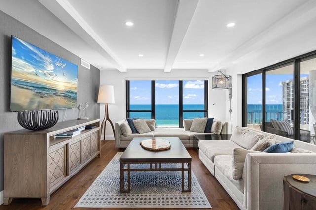 Bright condo living room with cream sectional sofas, beach artwork and windows overlooking the Gulf of Mexico