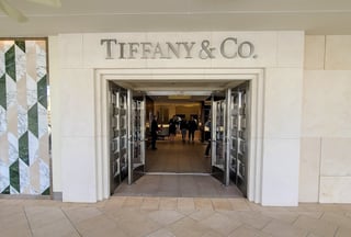 Limestone storefront entrance to Tiffany & Co. with open glass doors and shoppers inside