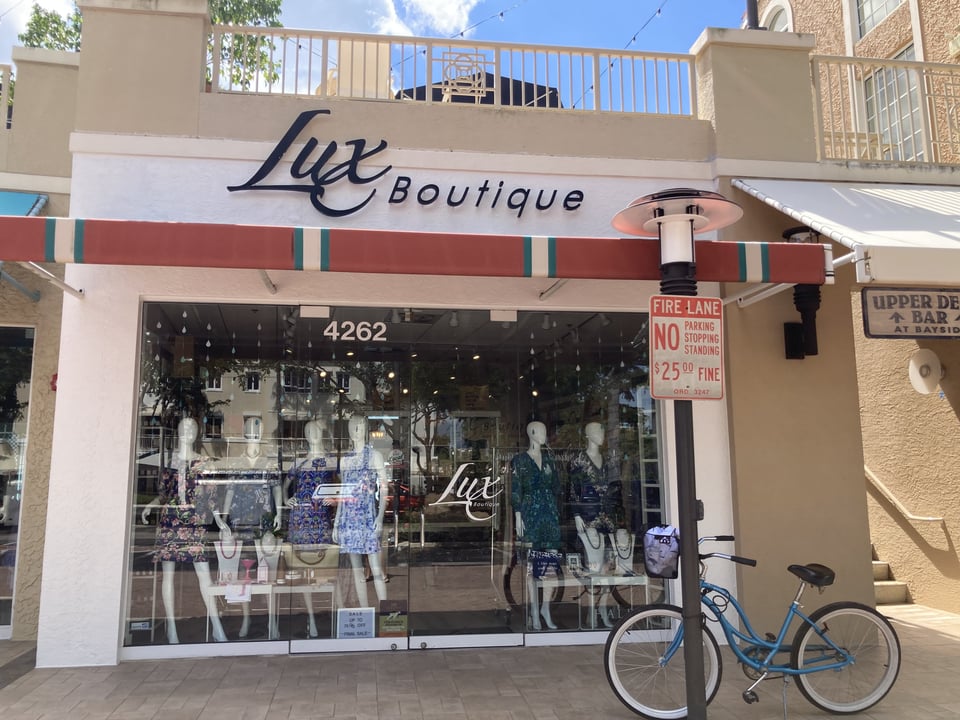 Storefront of Lux Boutique with dressed mannequins in the window and a blue beach cruiser parked out front