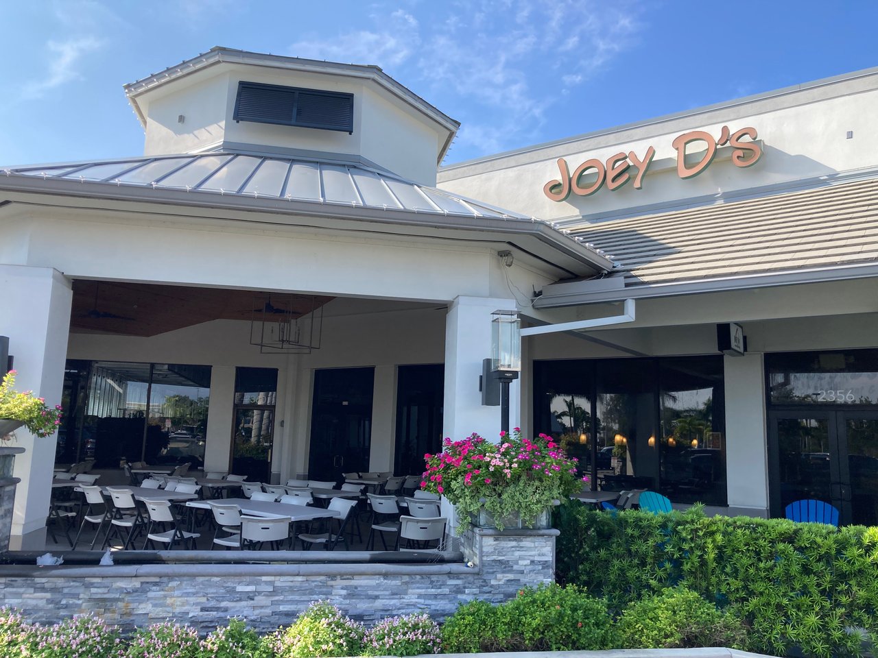 Exterior of Joey D's Italian Restaurant with covered patio seating, pink flowers and blue sky
Sorry, something went wrong
