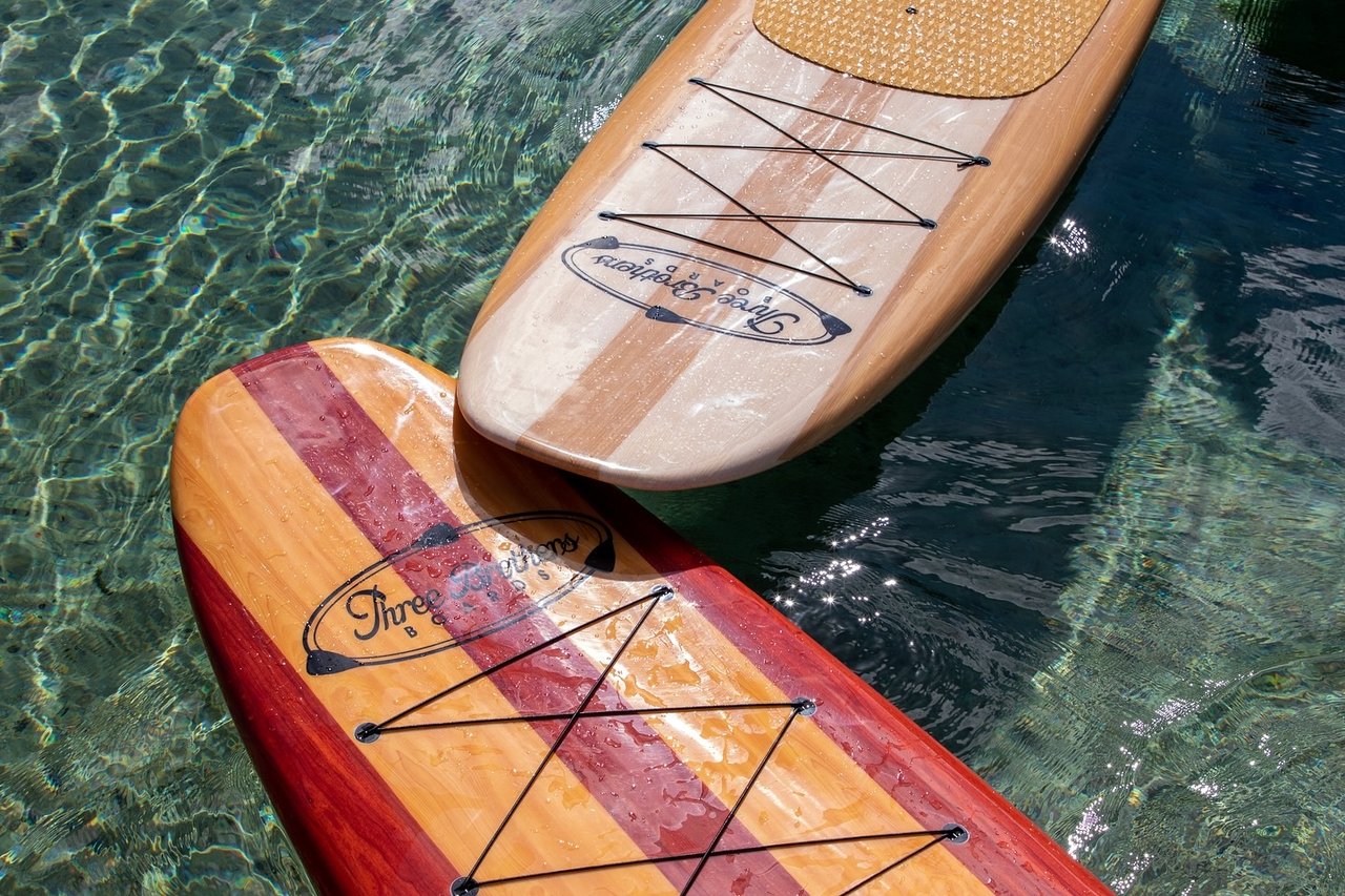 Two Three Brothers wooden stand-up paddleboards floating on clear water