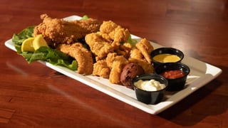 Platter of cornmeal catfish, fried shrimp and hush puppies with lemon and three dipping sauces