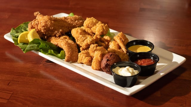 Platter of cornmeal catfish, fried shrimp and hush puppies with lemon and three dipping sauces