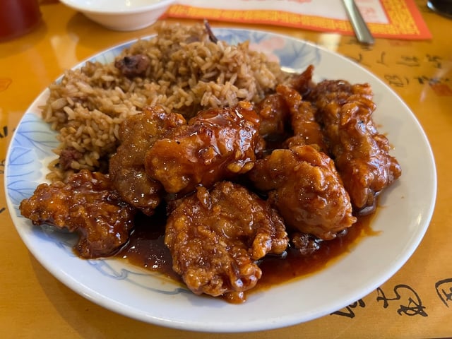 Plate of sticky glazed fried chicken with pork fried rice on a decorative blue and white plate