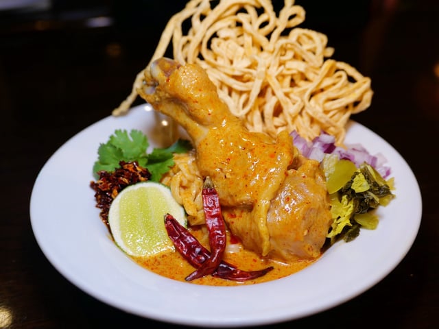 Northern Thai khao soi with chicken drumstick, crispy noodles, lime, dried chili and pickled greens
