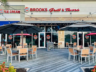 Brooks Grill & Tavern entrance with outdoor patio tables, umbrellas and string lights