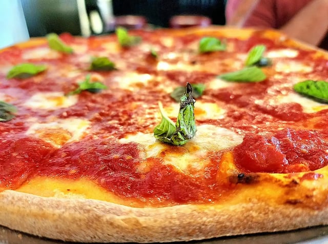 Close-up of a margherita pizza with tomato sauce, melted mozzarella and fresh basil leaves on a crisp crust