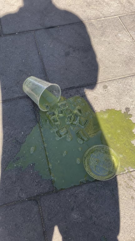 Spilled Green Iced Drink On Outdoor Stone Pavement Realistic Urban Documentary Photography generated image