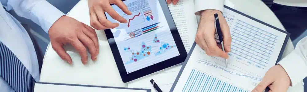 Buyer agents preparing for an appointment with charts and data on tablets and paper.