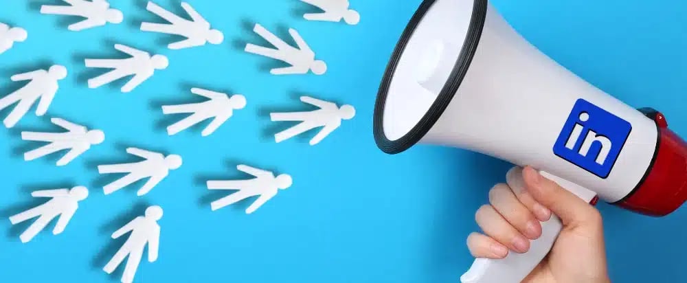 Megaphone with LinkedIn logo amplifying towards paper figures on blue background,
