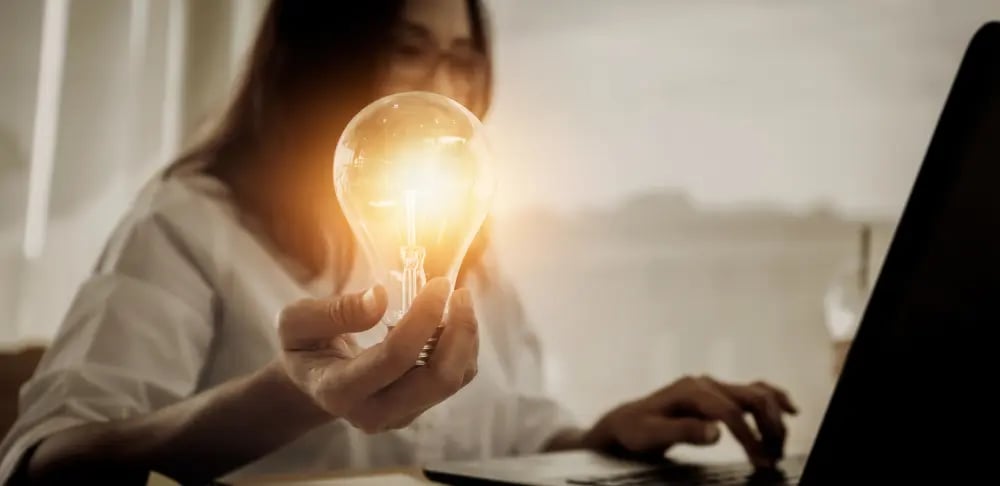 Idea Generation for Realtors - Person Holding a Light Bulb While Working on Laptop,