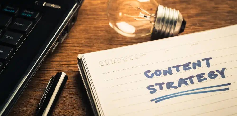 Notebook with 'Content Strategy' text next to a lightbulb and laptop,
