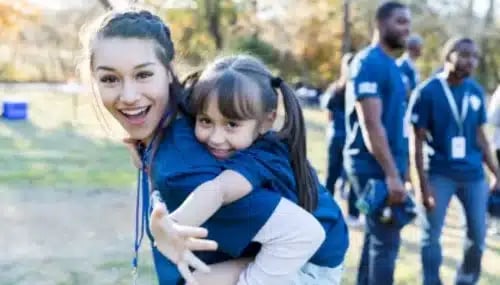 Real Estate Agent Bonding with Community - Smiling Woman with Child at a Local Event Highlighting Grassroots Lead Generation