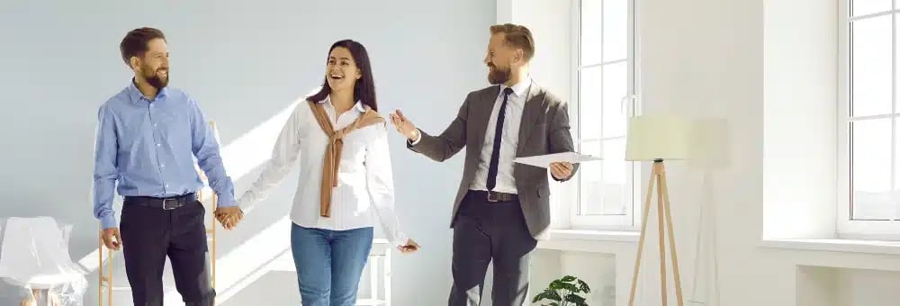 Real Estate Agent Marketing - Agent showing a home to a happy couple, representing value for home buyers