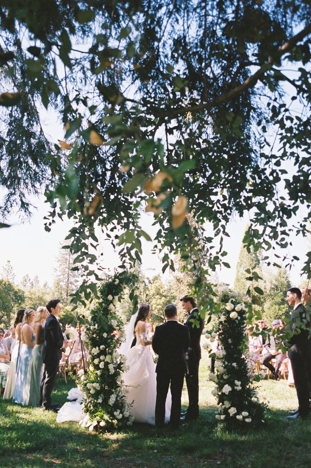 Couple exchanging vows under a floral arch on the West Lawn