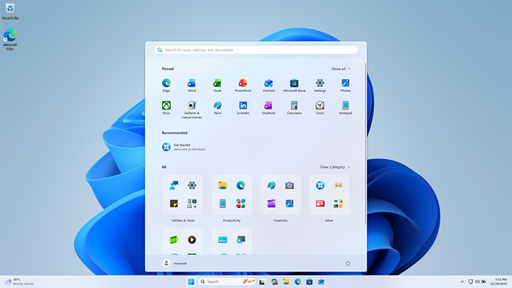 Área de trabalho do Windows 11 com o menu Iniciar e a barra de tarefas centralizados. O papel de parede abstrato tem tons de azul claro.