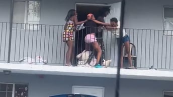 Women fight on a complex's balcony