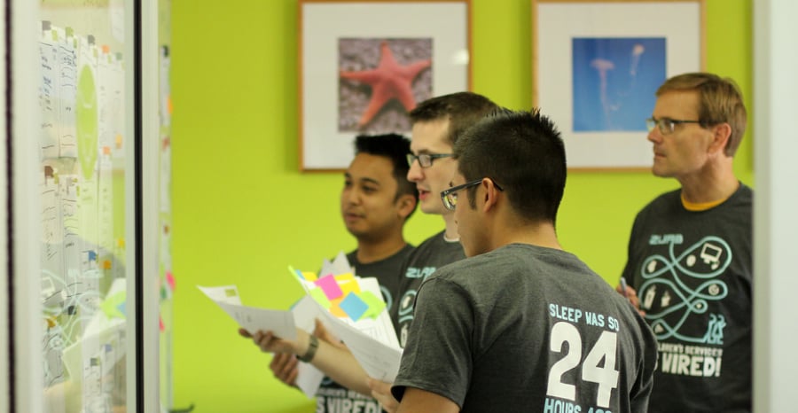 A team of designers critiquing design work at the whiteboard.