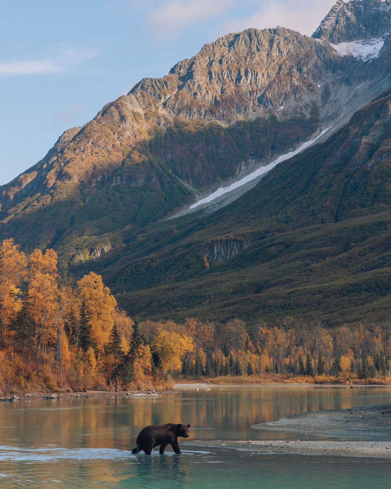 Snow-capped mountains reflected in the window of a rustic wood cabin, Alaska
