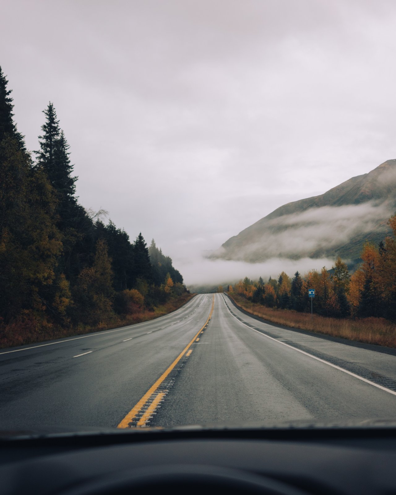 A rustic wood cabin with an American flag and a vintage orange pickup parked outside, Alaska