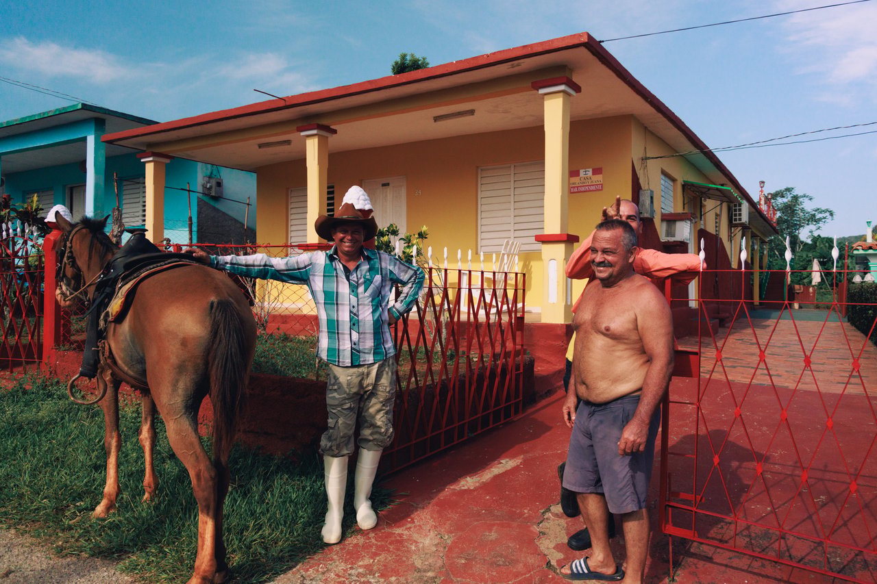 A man with a horse and a neighbour by a red gate in a Viñales village, Cuba