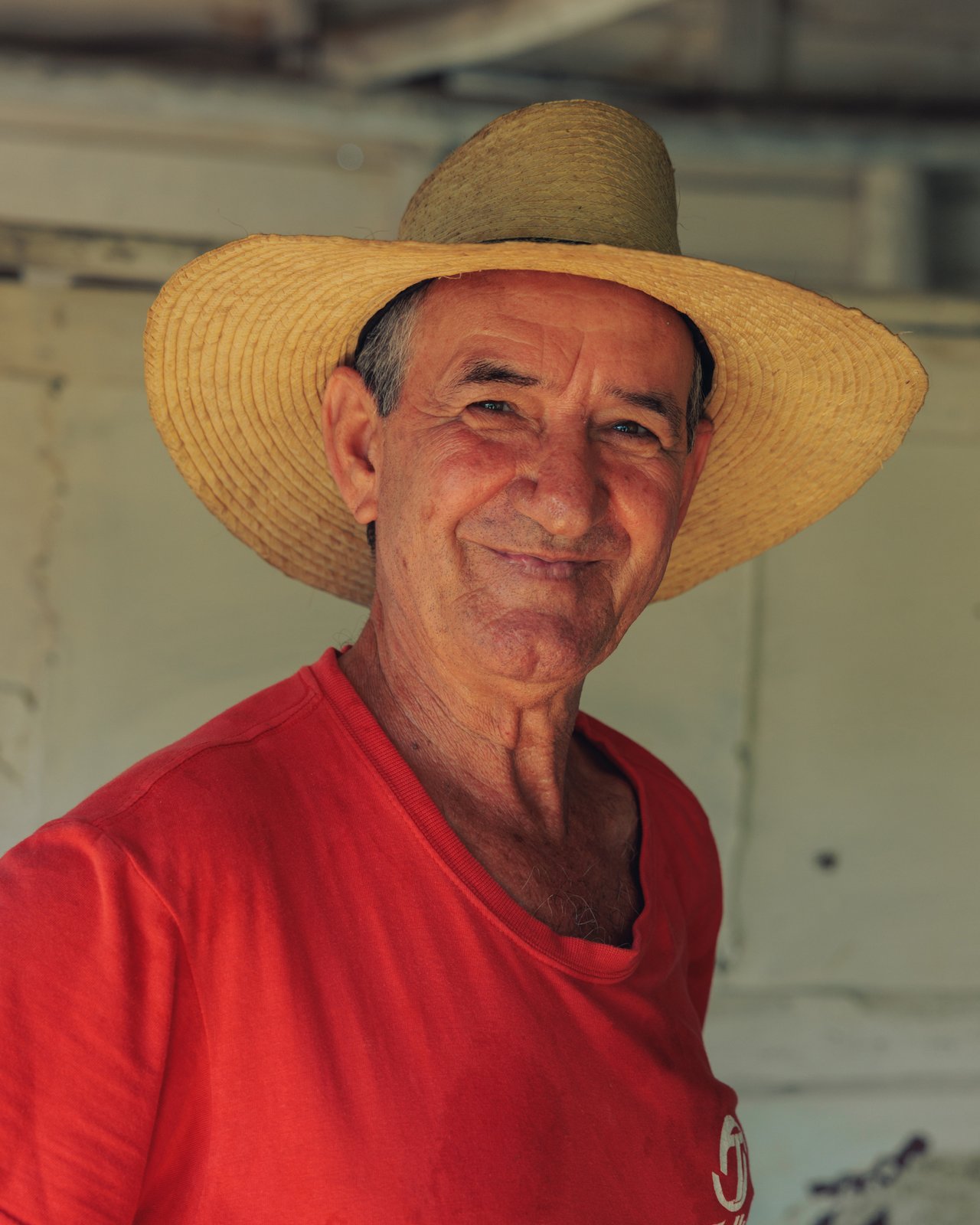 A portrait of a smiling guajiro farmer in a straw hat and red shirt, Cuba
