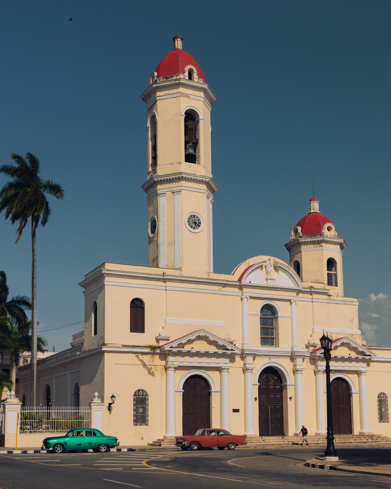 The twin red-domed towers of the Cienfuegos cathedral, a vintage car passing, Cuba