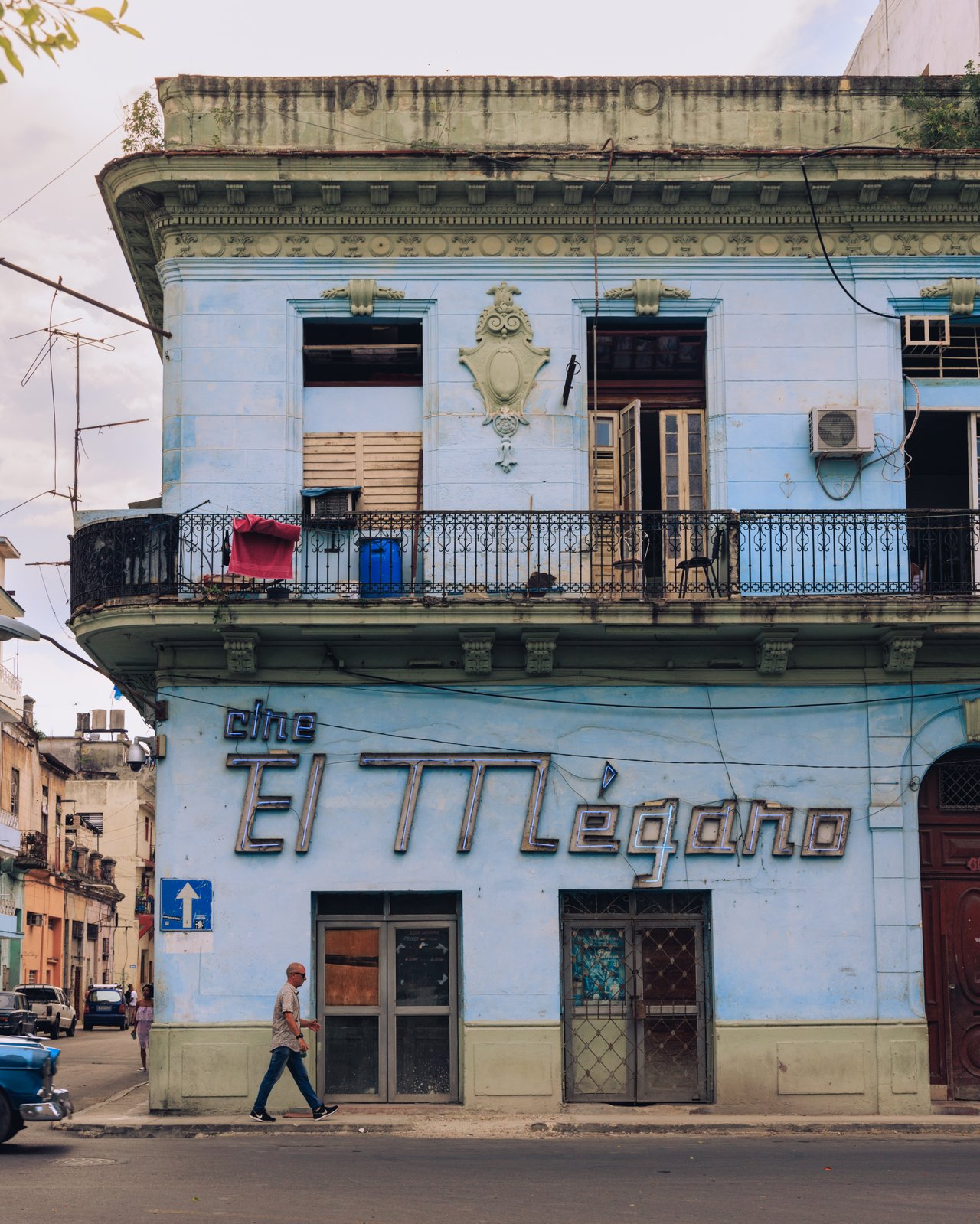 The old 'Cine El Mégano' cinema facade, a figure crossing the street, Havana, Cuba