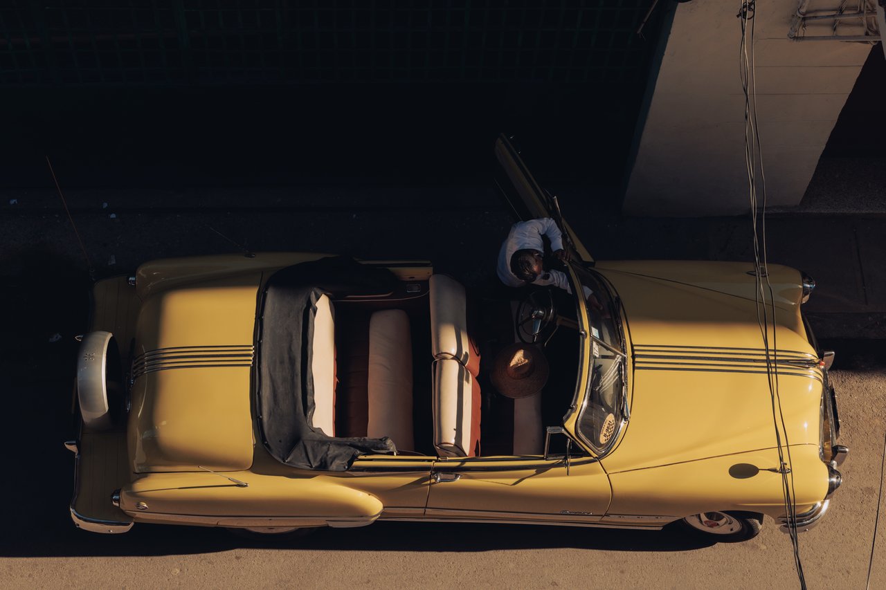 An overhead of a yellow classic convertible with its driver, Havana, Cuba