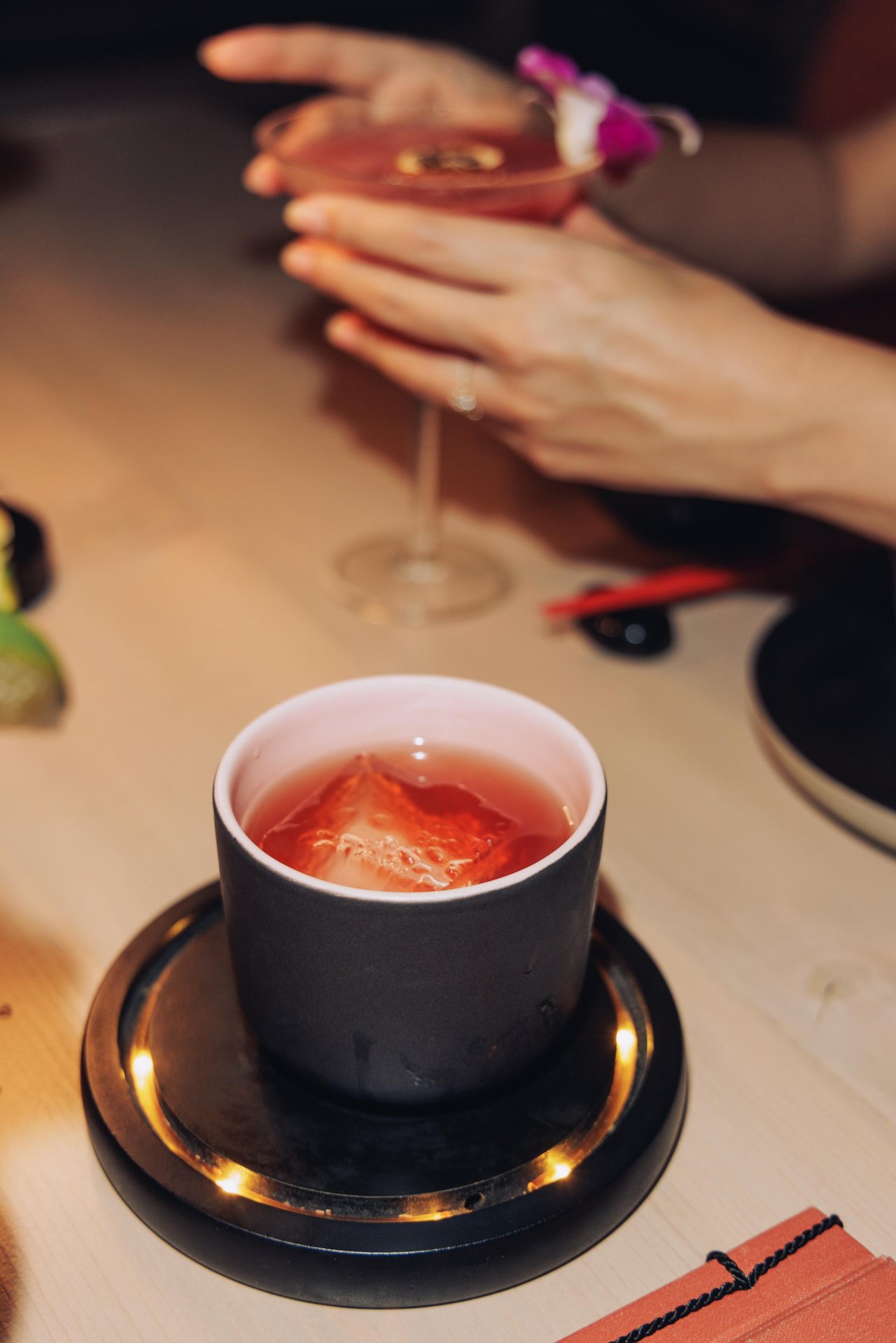 A hand resting beside a cup at a sunlit table, Four Seasons Oʻahu