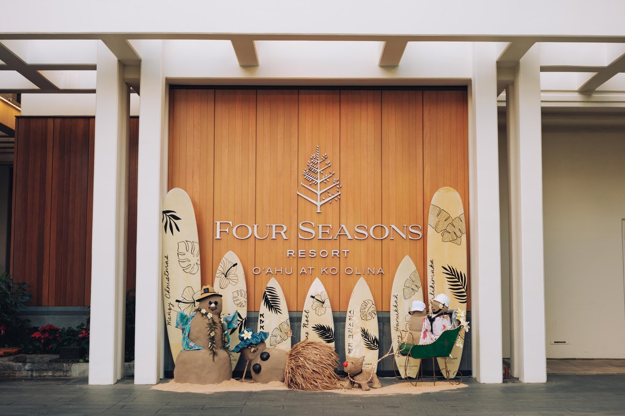 The resort entrance sign flanked by decorated surfboards and a sand snowman, Four Seasons Oʻahu at Ko Olina