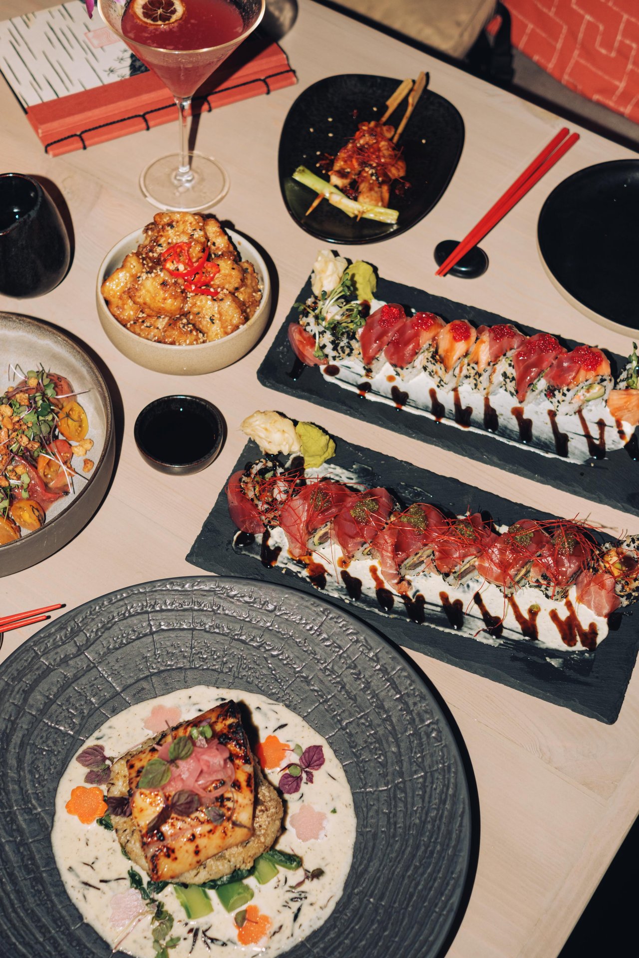 An overhead izakaya spread with sushi and a plated fish course, Four Seasons Oʻahu