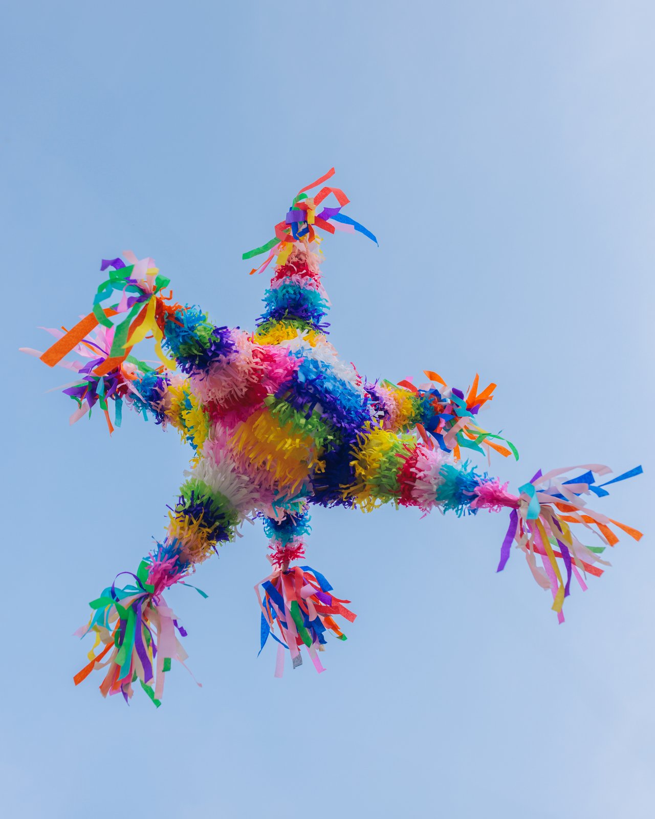 A seven-point star piñata hanging against a clear blue sky